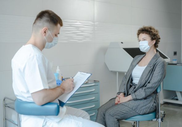 Уролог у медичному кабінеті спілкується з пацієнтом, пояснюючи процедуру масажу простати.