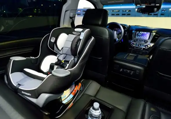 Мама пристібає малюка в дитячому автокріслі в салоні автомобіля